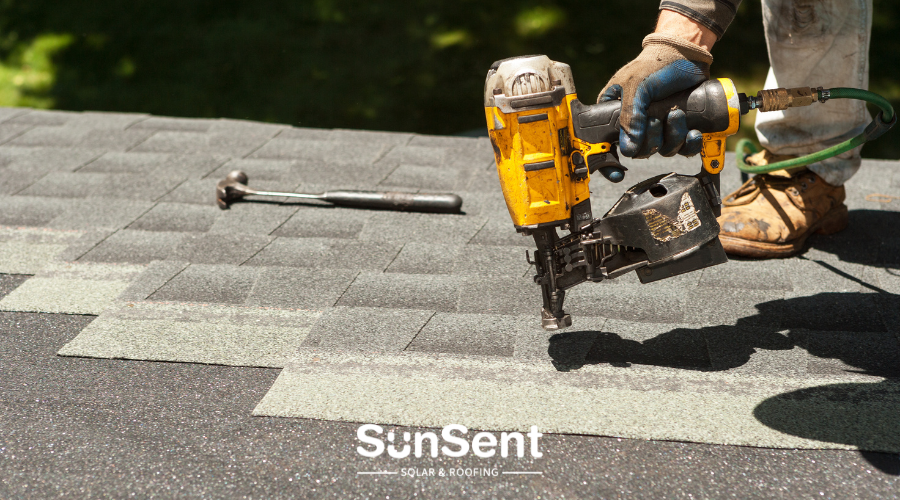 SunSent Solar and Roofing technician installing asphalt shingles with a roofing nailer during a roof replacement.