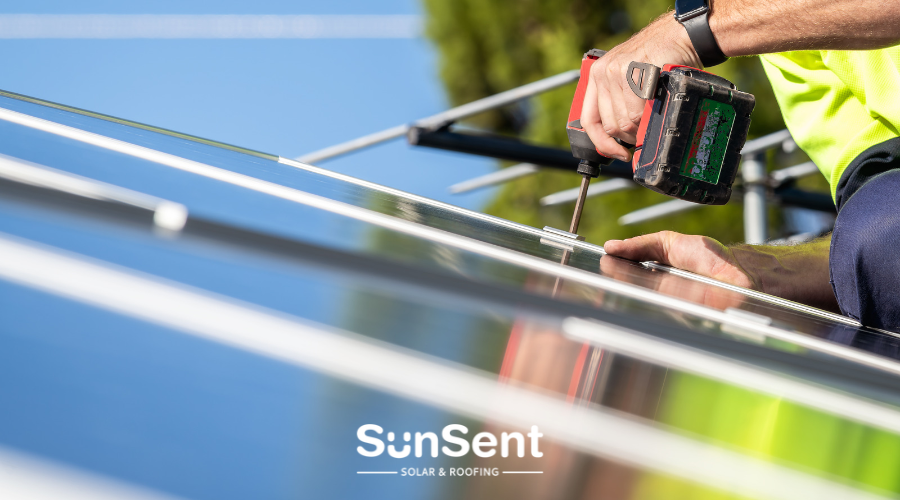 Solar technician using a power drill to secure rooftop solar panels during a professional SunSent solar power installation.