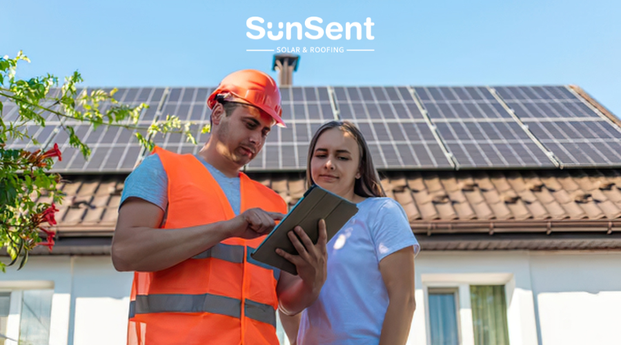 SunSent technician and homeowner discussing a solar power installation in front of a home with rooftop solar panels.